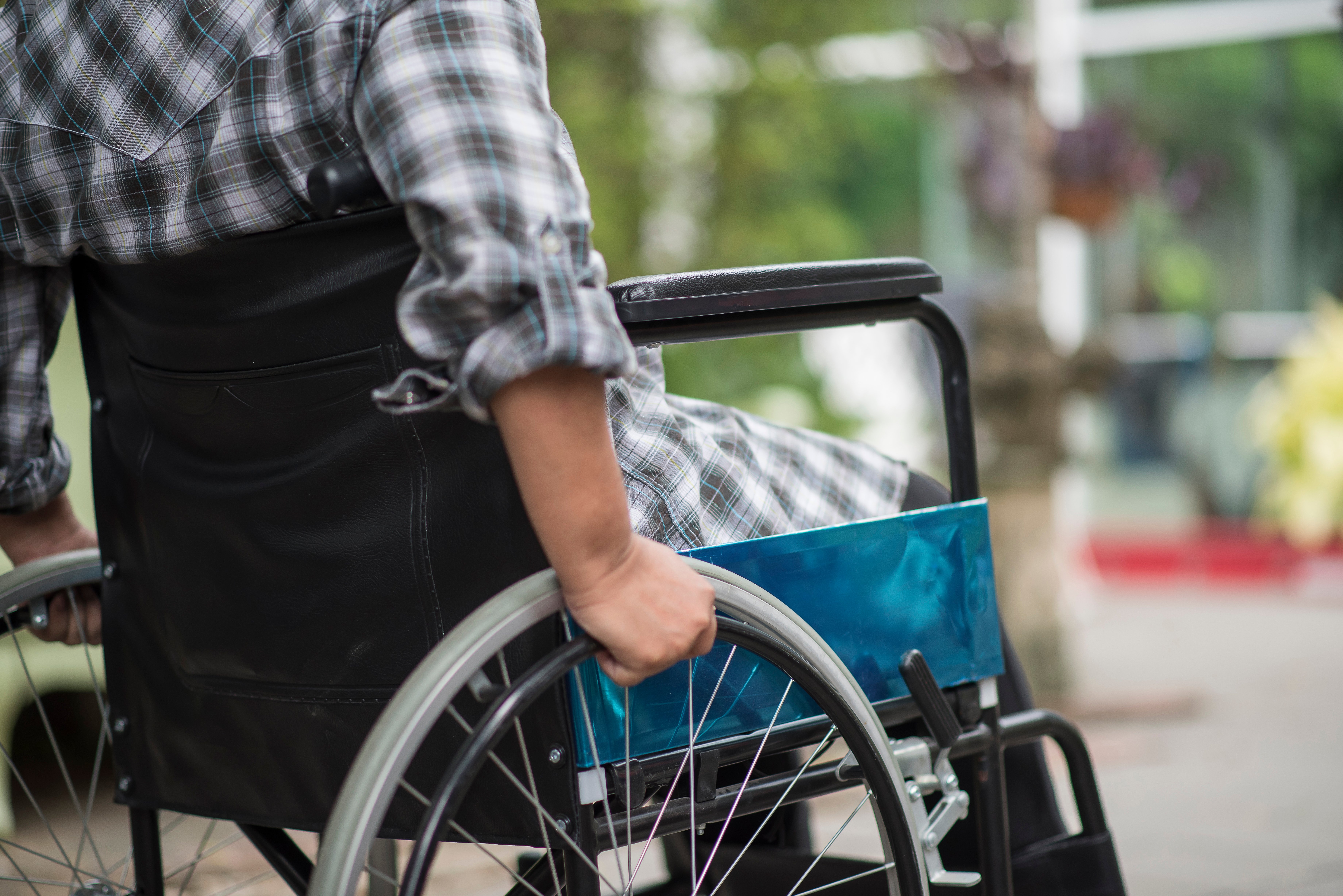 close-up-of-senior-woman-hand-on-wheel-of-wheelchair-during-walk-in-hospital